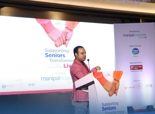 Dr. Tanmoy Karmakar addressing the audience beside the event presentation screen.
